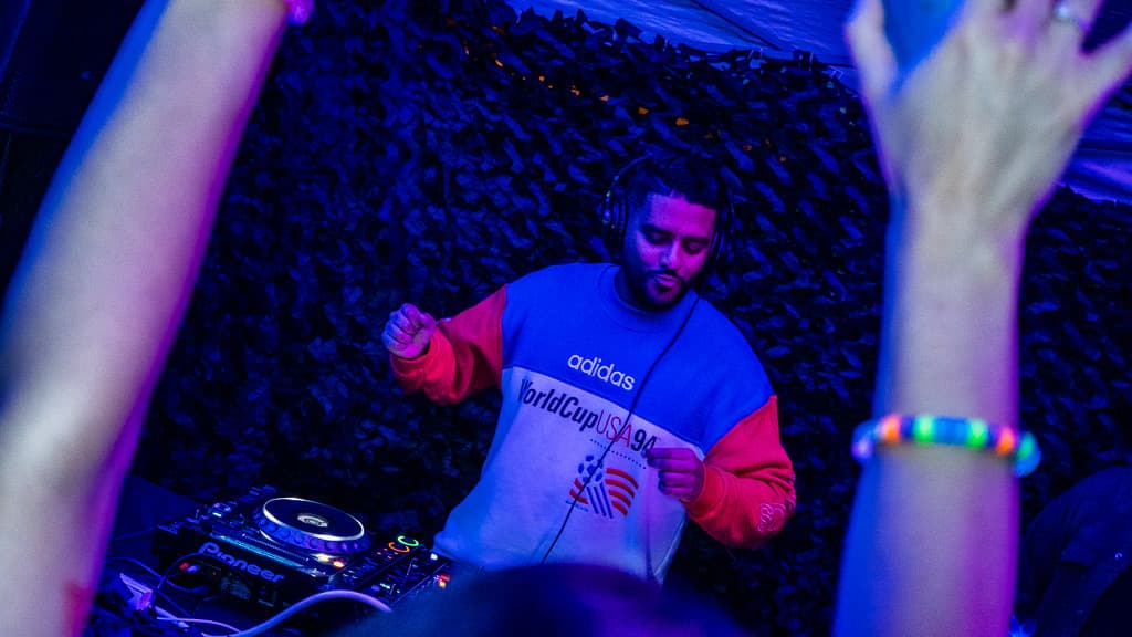 DJ booth under pink neon with the crowd in front